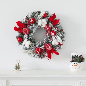 Christmas wreath with red bows, cotton balls and snow effect needles on white wall