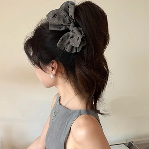 Close-up of grey fabric bow hair claw clip with black bow prints on a high ponytail