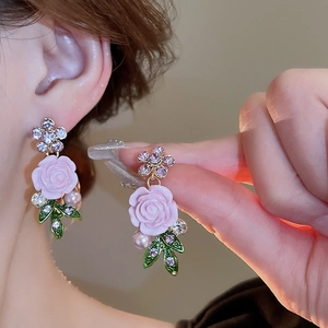 Detail of pink resin rose earring with green enamel leaves and sparkling crystal accents