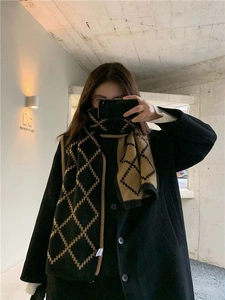 Detail of checkered knit scarf in black and camel plaid worn with a stylish winter coat