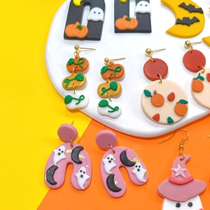 Close-up of handmade polymer clay Halloween earrings featuring ghosts and pumpkins