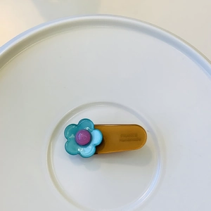 Detailed close-up of blue floral hair clip with FRANCE Handmade engraved text on back