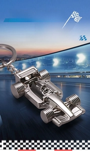 Macro shot of silver metal F1 race car keychain with polished mirror finish on track