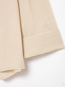Detailed close-up of rolled cuff on a beige linen-style blouse showing refined stitching