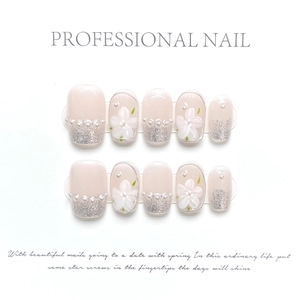 Detail of pink press-on nails with silver glitter tips, 3D floral art, and pearl accents