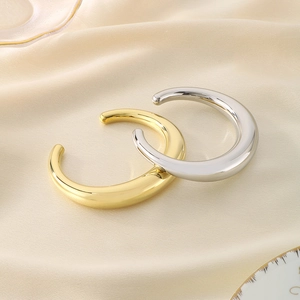 Vue détaillée de bracelets joncs en forme de C dorés et argentés sur fond de satin beige