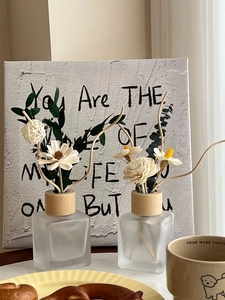 Close-up of reed diffusers in frosted glass bottles with dry flowers in a cozy setting