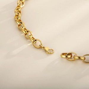 Close-up of golden thick chain link necklace and bracelet set with lobster clasp detail