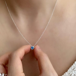 Close-up of a s925 silver necklace featuring a heart-shaped blue zircon pendant on model