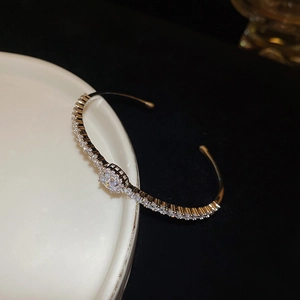 Close-up of gold-plated open bangle with pave cubic zirconia and center round stone