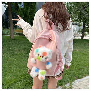 Dettaglio di uno zaino rosa con una grande decorazione a forma di gatto di peluche colorato