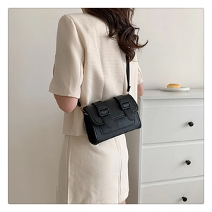 Rear view of a model wearing a black minimalist crossbody bag with decorative buckles