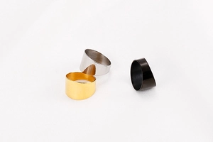 Three minimalist wide band rings in gold, silver, and black on a textured white background