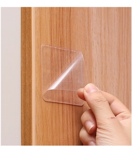 Macro view showing the flexibility of a transparent double-sided adhesive pad on wood