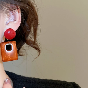 Close-up of vintage geometric acrylic square earrings in red and brown worn by a model