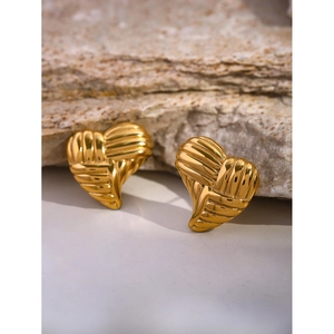 Detailed macro view of 18k gold heart earrings with textured horizontal stripes on rock