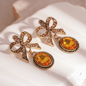 Detailed view of vintage bow earrings featuring amber stones and gold metal frame