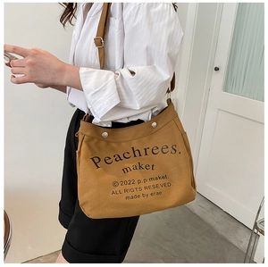 Detail view of khaki canvas tote bag with adjustable shoulder strap and side pockets