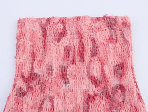 Detalle de tela fruncida con estampado floral rosa y textura elástica de pliegues