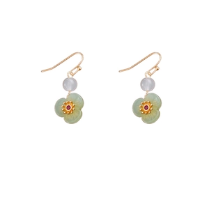 Gold plated flower earrings with green petals and white beads on a white backdrop