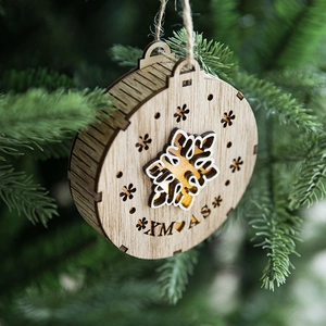 Round wooden Christmas ornament with LED light, snowflake design hanging on a tree branch