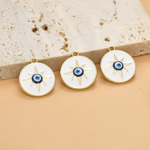 Macro shot of three golden enamel evil eye star charms on a textured stone surface