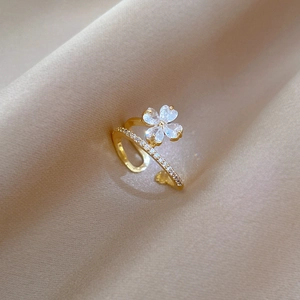 Macro view of adjustable clover flower ring with heart-shaped zircons on silk background