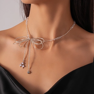 Close-up of glass beaded bow necklace with silver heart and star charms on a model