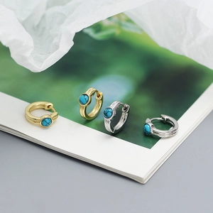 Macro detail of gold and silver S925 sterling silver hoop earrings with blue turquoise inlay