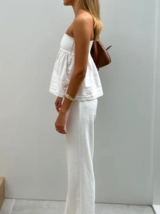 Détail du haut bustier en coton blanc et pantalon large avec sac à main en cuir marron
