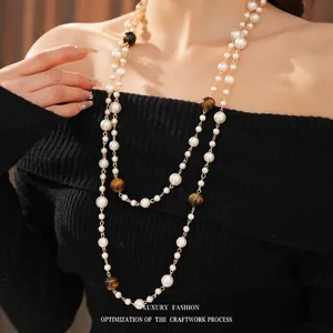 Double-layer long pearl necklace with tiger eye beads on elegant black sweater
