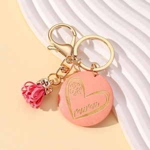 Detail of pink wooden keychain with engraved MAMA heart pattern and leather tassel