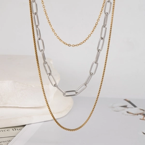 Elegant multi-layer stainless steel necklace in gold and silver finish on artistic props