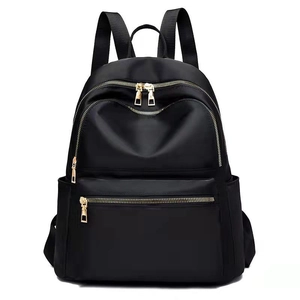 Detail view of black nylon backpack with golden zippers and multiple storage pockets
