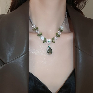 Dettaglio della collana con fiori e foglie e zircone verde a goccia su una modella