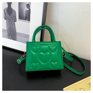 Détail du sac à main en cuir vert avec motif cœur gaufré et bandoulière réglable