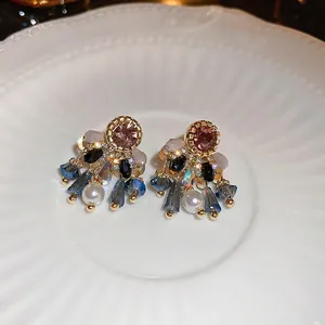 Exquisite retro gold drop earrings with purple crystals and pearl on a white ceramic plate