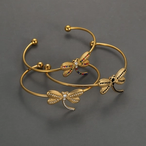 Minimalist 18K gold dragonfly bangle set with multicolored crystals on grey background