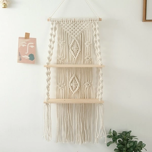Detail of bohemian hand-woven macrame shelf with wooden boards and decorative tassels