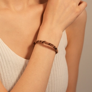 Detailed close-up of a leopard print faux fur cuff bracelet on a woman wrist