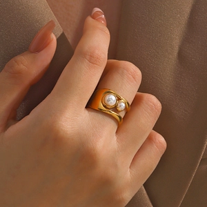 Elegant gold-plated stainless steel wave ring featuring two white pearls on a female finger