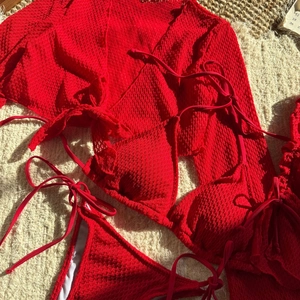 Dettaglio del bikini rosso tre pezzi in tessuto testurizzato con copri-costume coordinato