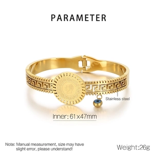 Detail of gold titanium steel bangle with coin relief, Greek pattern and evil eye charm