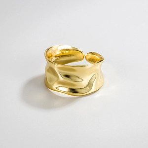 Macro detail of wide gold irregular textured ring featuring hammered metal surface design