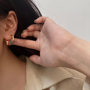 Close-up of golden hoop earrings with colorful enamel rings worn by a model