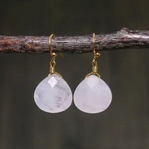 Detail of rose quartz teardrop earrings with handmade gold wire wrapping on wood