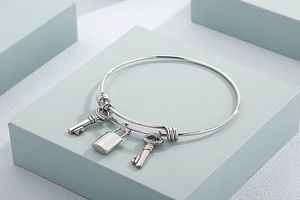 Detailed shot of a silver stainless steel bangle with lock and key charms on a blue block