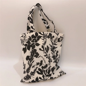 Detail of minimalist white cotton tote bag with black floral fern leaf print design
