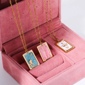 Detailed shot of gold tarot necklaces with colorful enamel pendants in a jewelry box