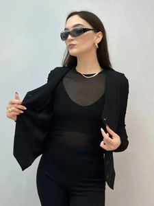 Detail of a chic black V-neck vest cardigan paired with sheer mesh top and suit pants